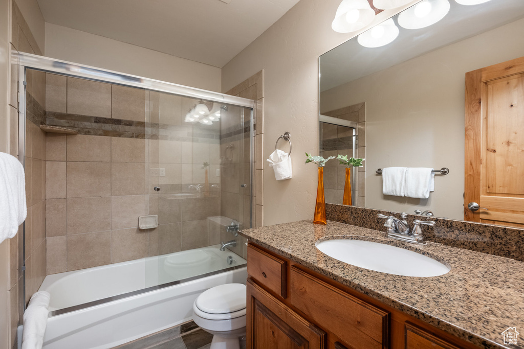 Bathroom with toilet, enclosed tub / shower combo, and vanity