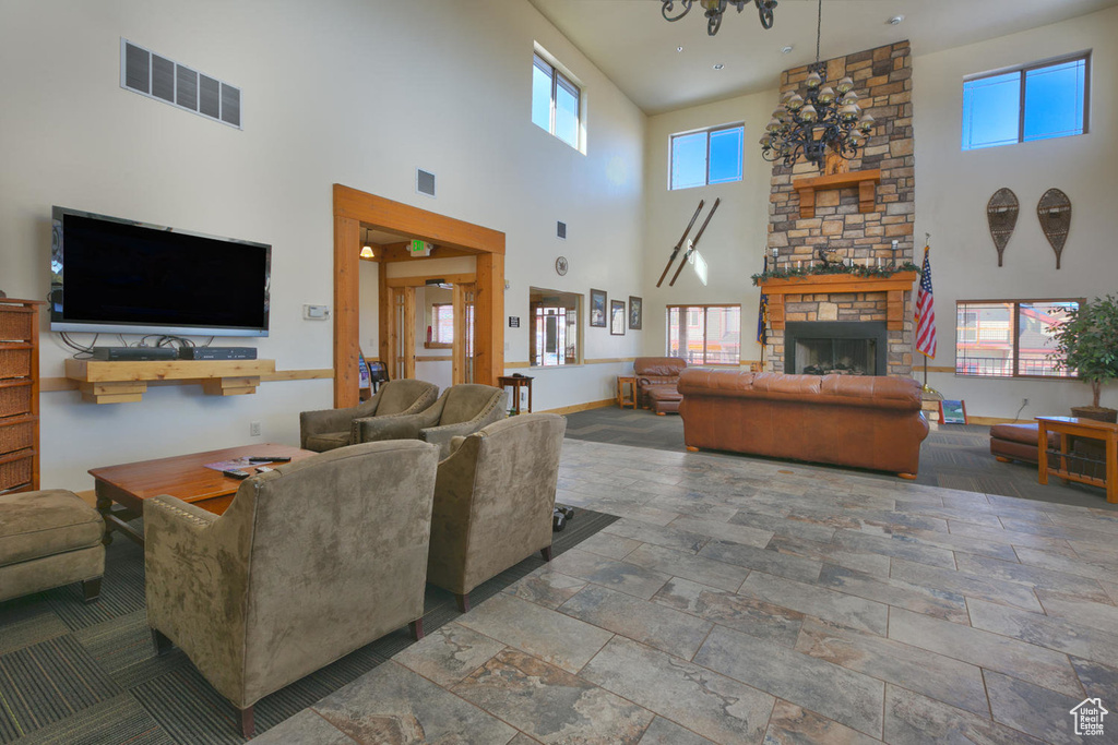 Living room with a towering ceiling, visible vents, a stone fireplace, and stone tile flooring
