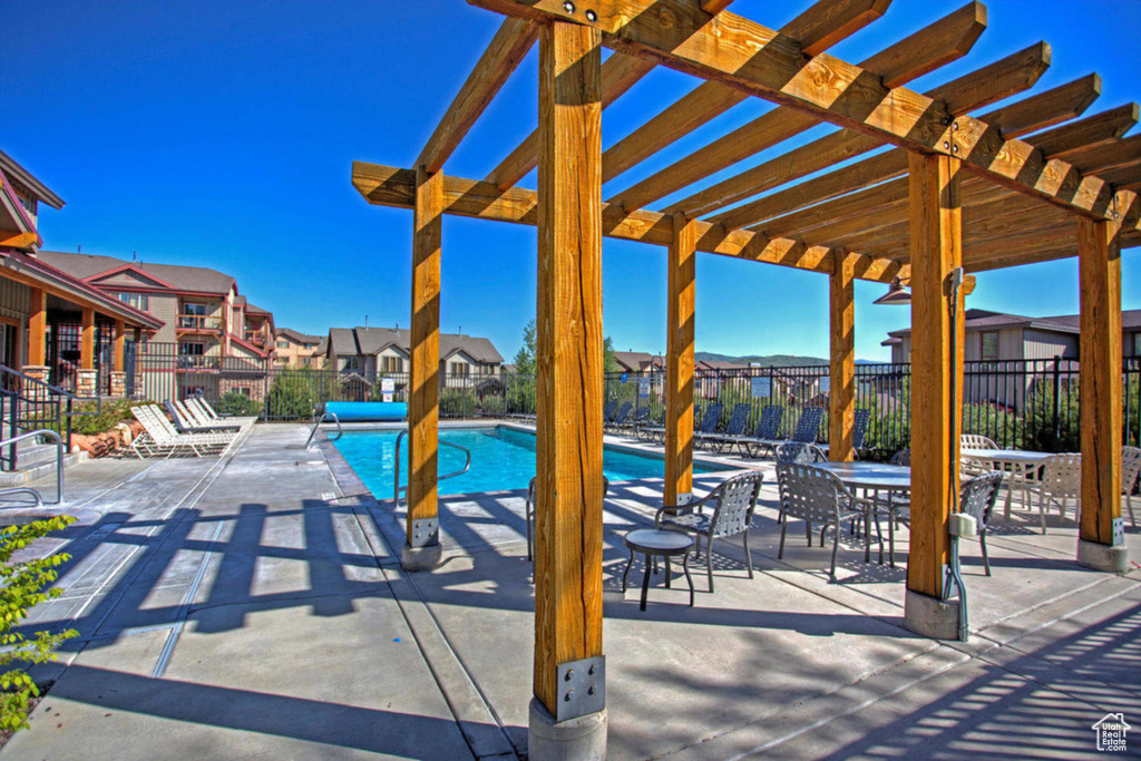 View of patio / terrace featuring fence, a pergola, a residential view, and a community pool