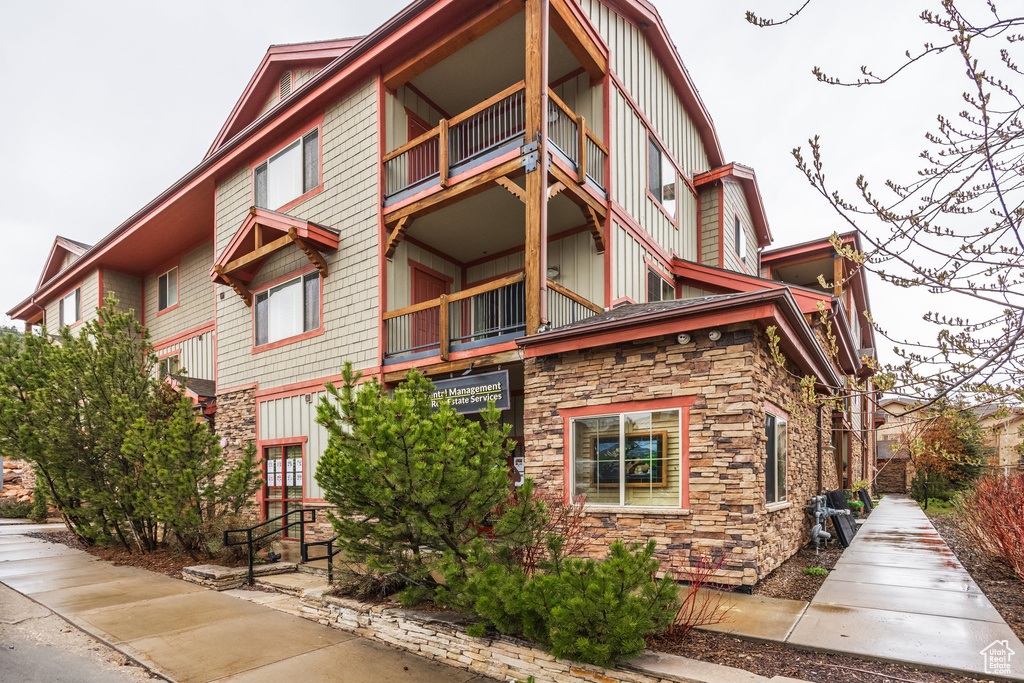 Exterior space featuring board and batten siding, a balcony, and stone siding