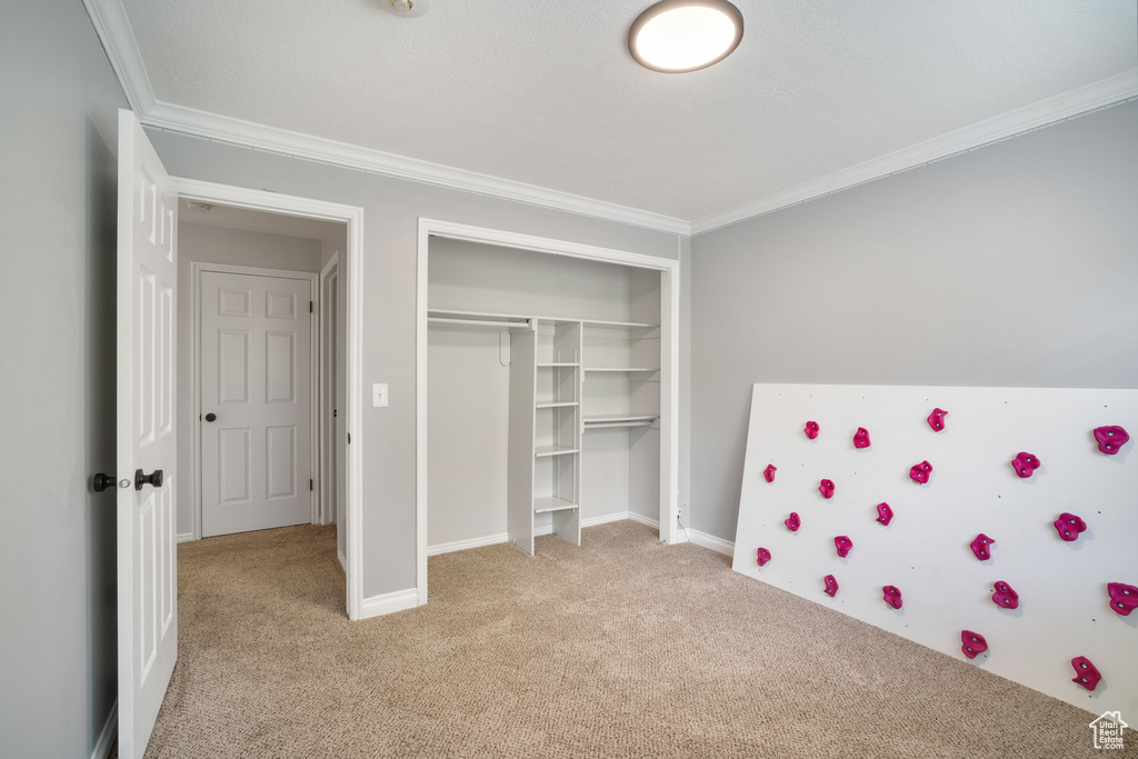 Unfurnished bedroom with crown molding, a closet, baseboards, light carpet, and refrigerator