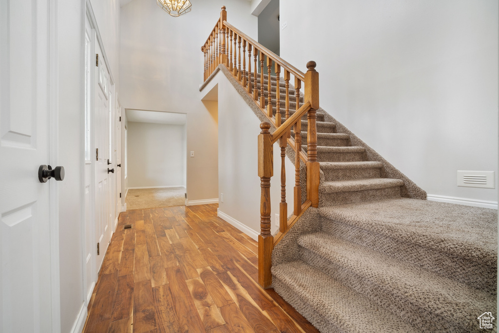Stairs with a high ceiling, visible vents, wood finished floors, and baseboards
