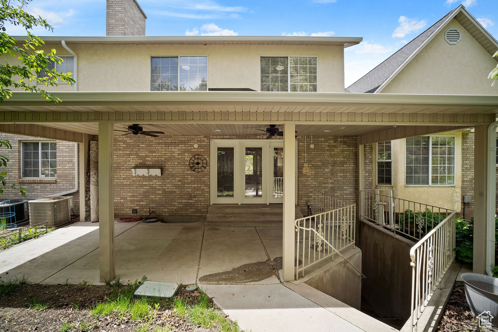 Rear view of property featuring stucco siding, a ceiling fan, and brick siding
