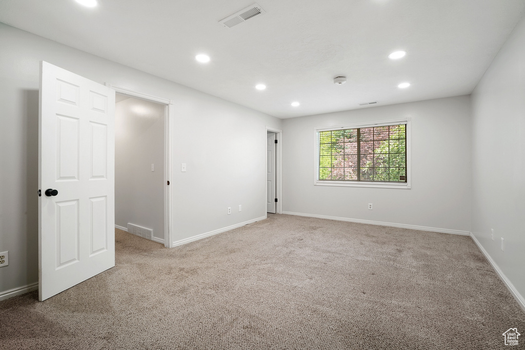 Carpeted spare room featuring baseboards, visible vents, and recessed lighting