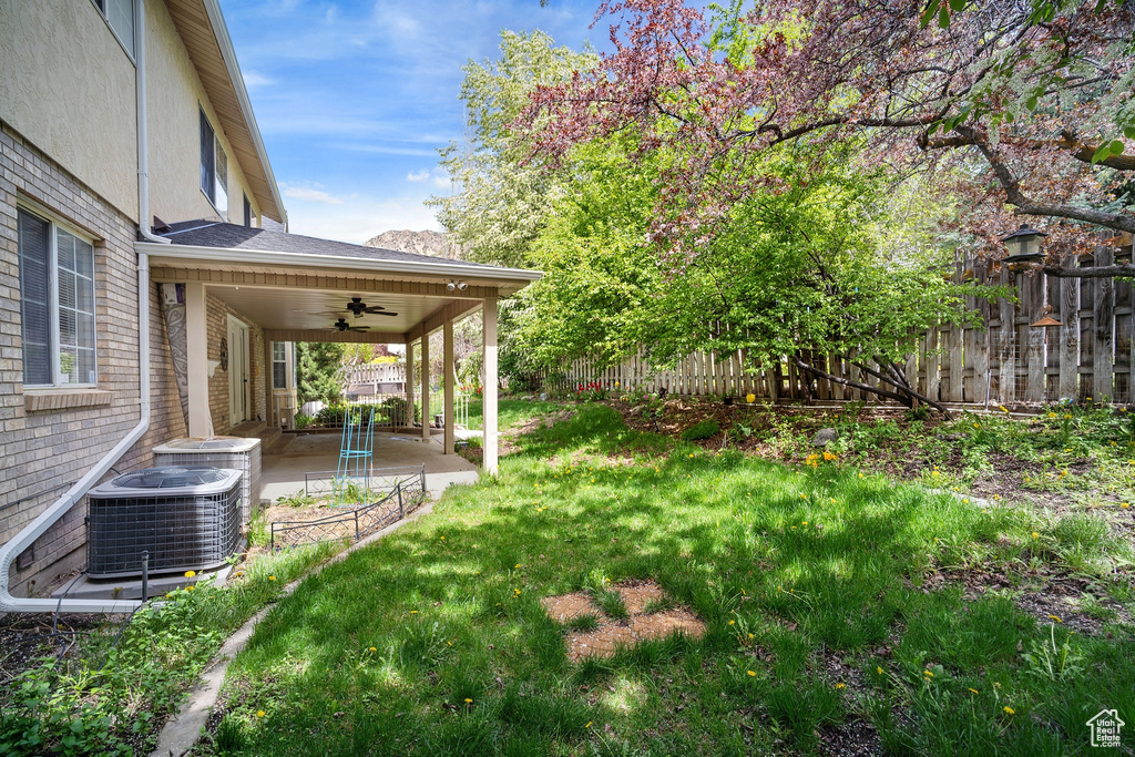 View of yard featuring a patio, fence, ceiling fan, and central AC