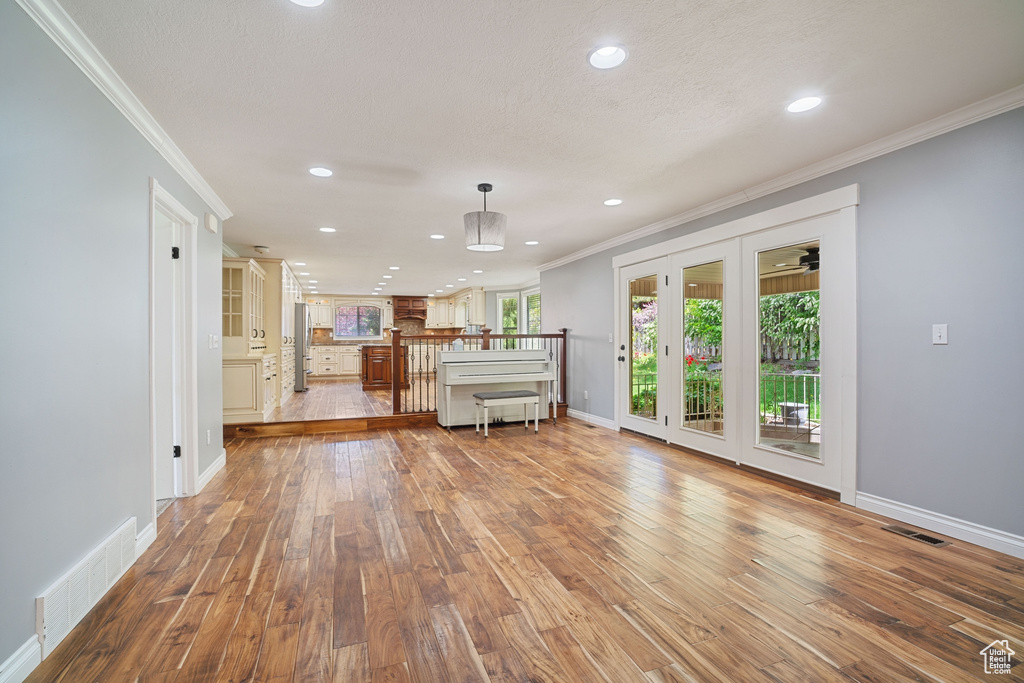 Unfurnished living room featuring visible vents, recessed lighting, ornamental molding, and baseboards