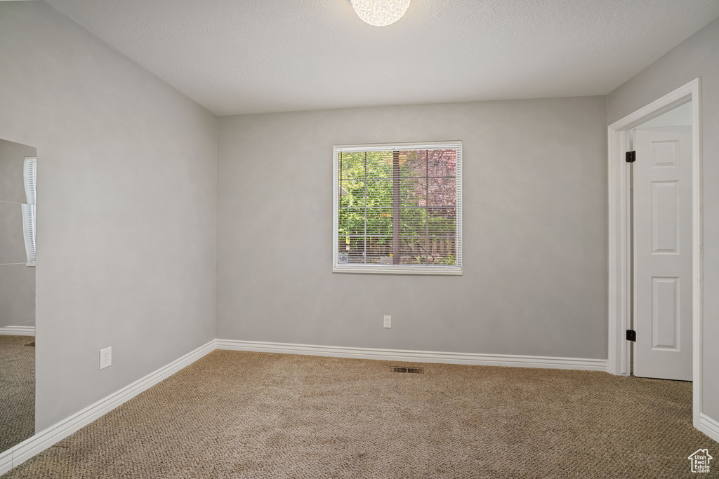 Unfurnished room featuring baseboards, visible vents, and carpet