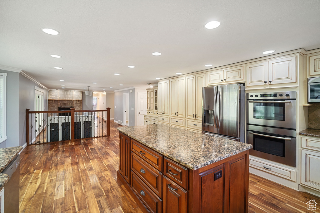 Kitchen with cream cabinetry, stainless steel appliances, stone countertops, and ornamental molding