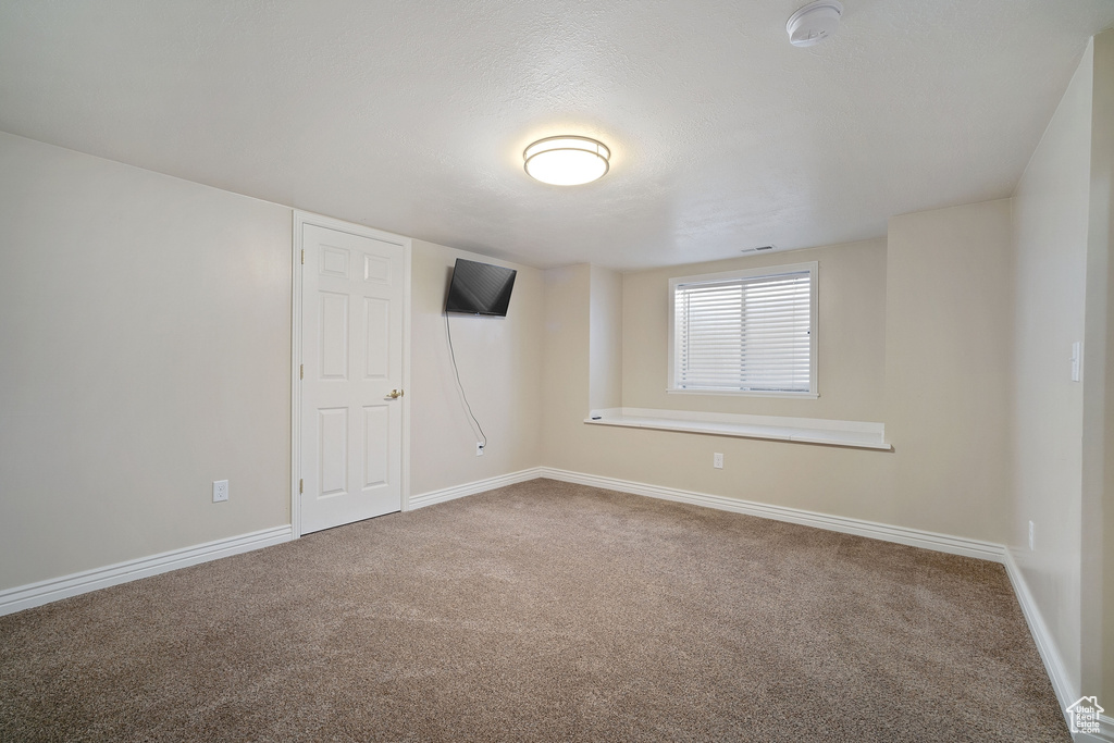 Carpeted spare room featuring baseboards