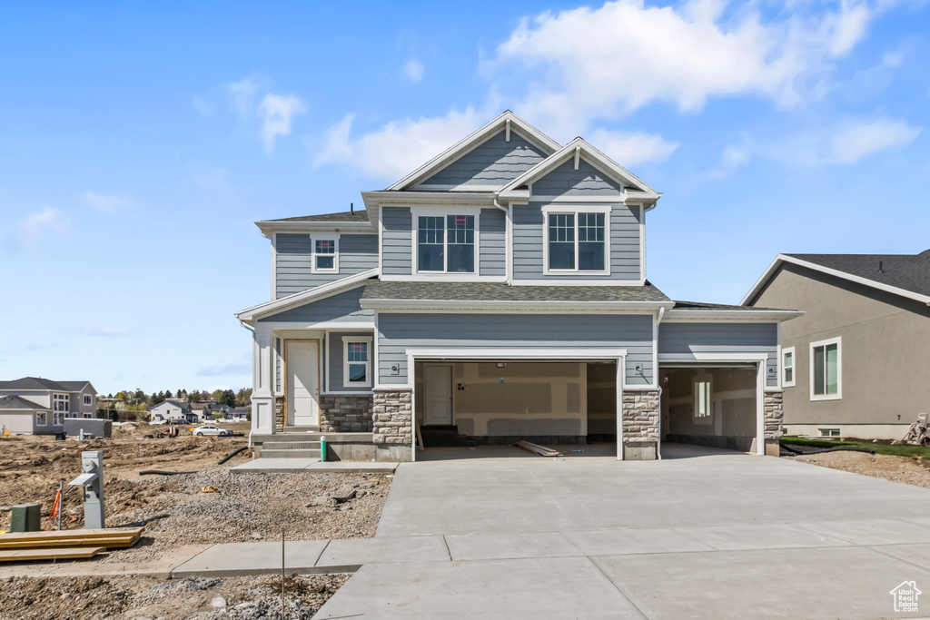 Craftsman-style house featuring a garage, concrete driveway, and stone siding