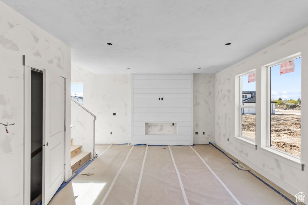Unfurnished living room featuring stairs, concrete flooring, and baseboards