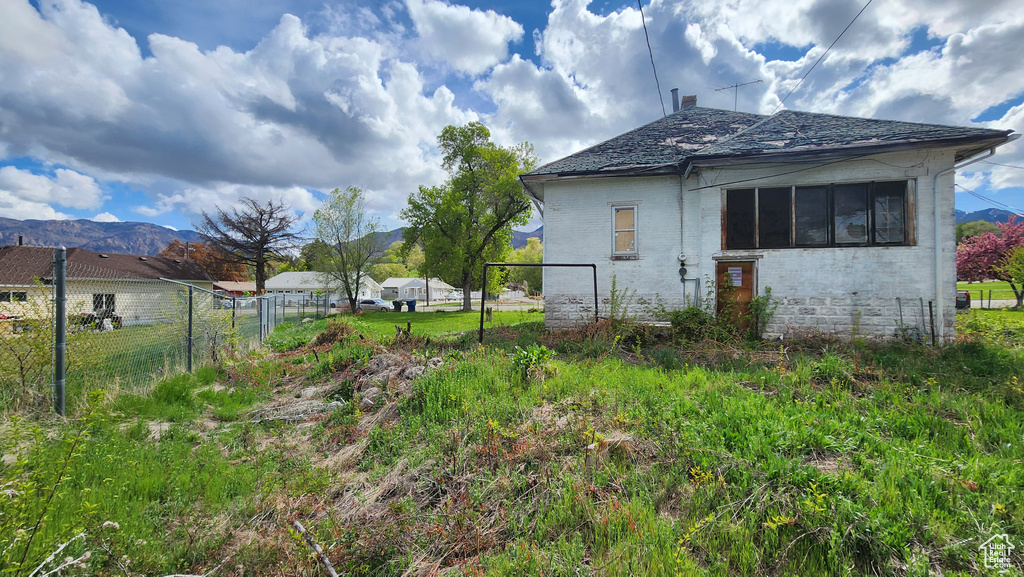 View of side of property with brick siding, fence, and a mountain view