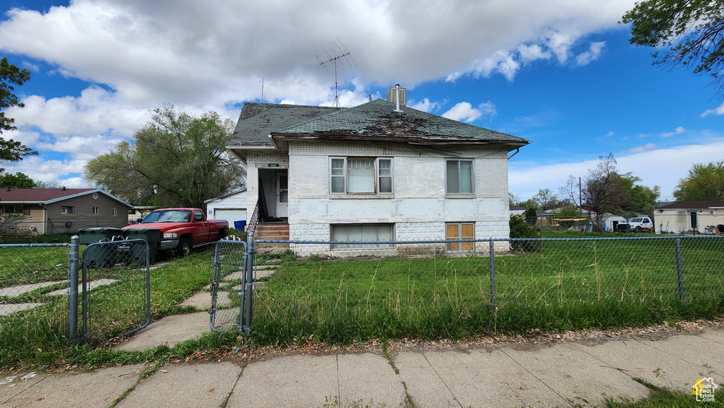 View of home\'s exterior with a garage, a fenced front yard, a gate, a lawn, and brick siding
