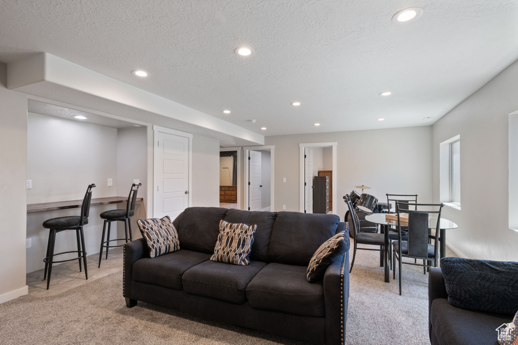 Living area featuring baseboards, recessed lighting, a textured ceiling, and light colored carpet
