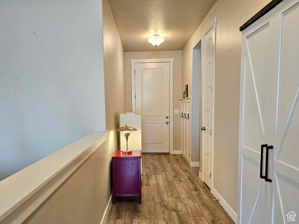 Corridor featuring a textured ceiling, baseboards, and wood finished floors