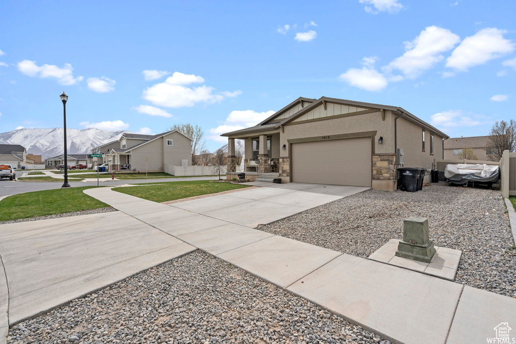 Craftsman-style home with a residential view, an attached garage, a front lawn, stone siding, and driveway