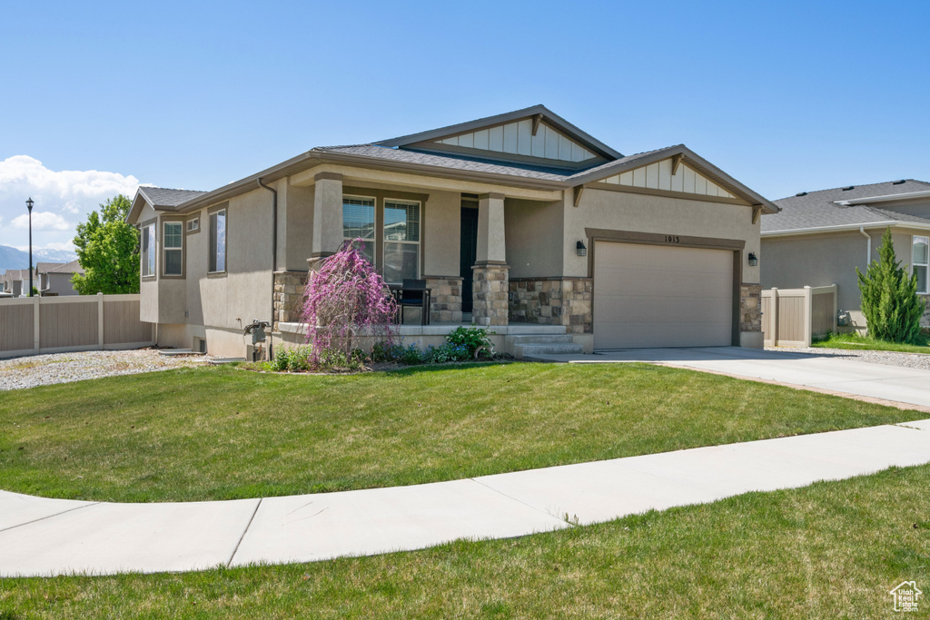 Craftsman inspired home with covered porch, driveway, a front yard, a garage, and fence