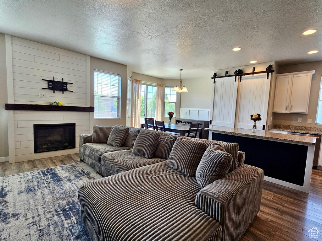 Living area featuring wood finished floors, a fireplace, recessed lighting, a barn door, and a textured ceiling