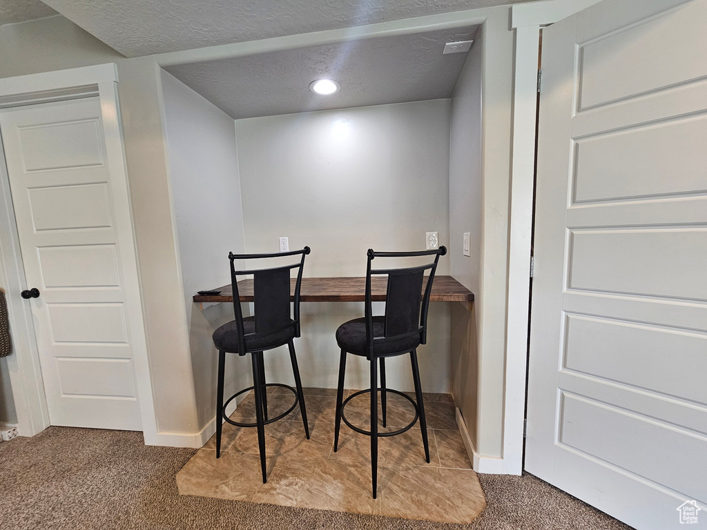 Interior space featuring a textured ceiling, baseboards, recessed lighting, and carpet