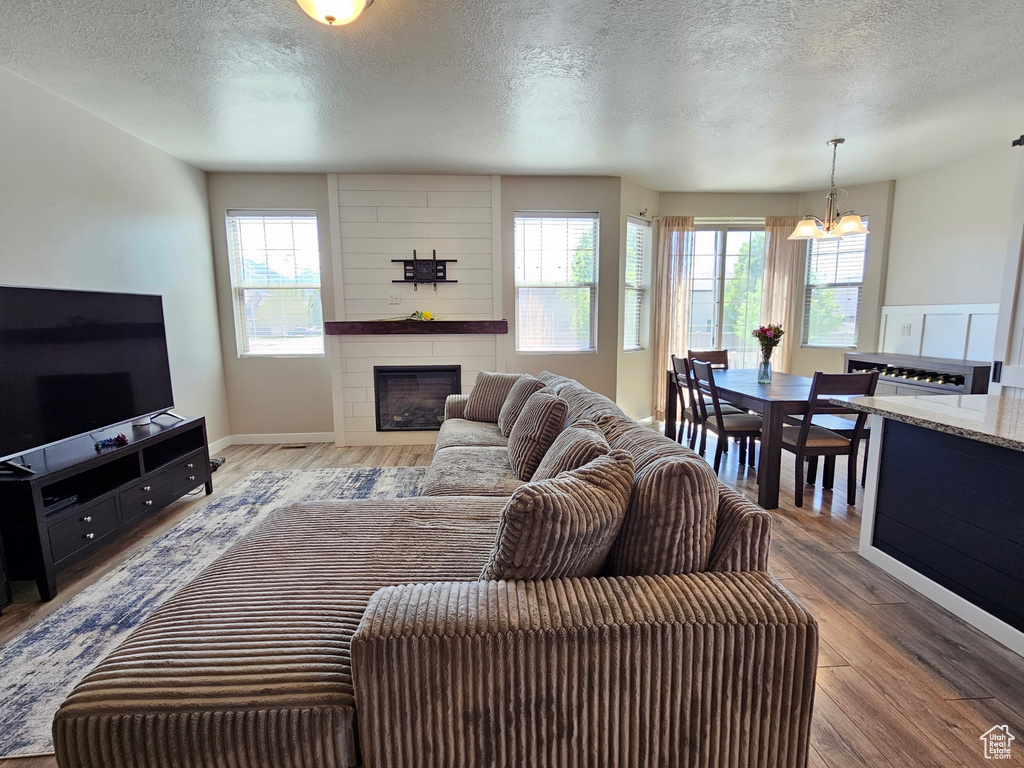 Living room featuring a wealth of natural light, a fireplace, a textured ceiling, and a notable chandelier
