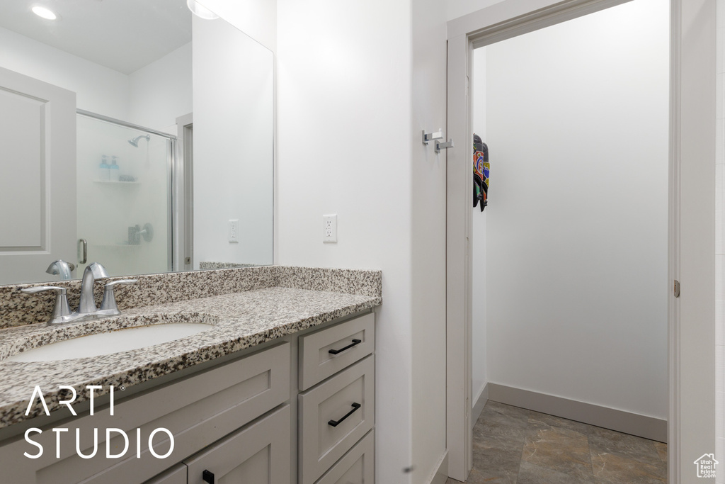 Full bath featuring a stall shower, stone finish flooring, vanity, and baseboards