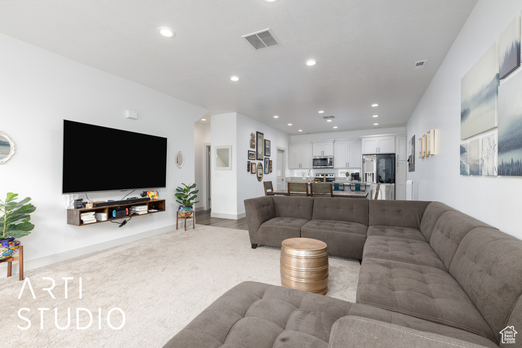 Living room with recessed lighting, visible vents, and light colored carpet