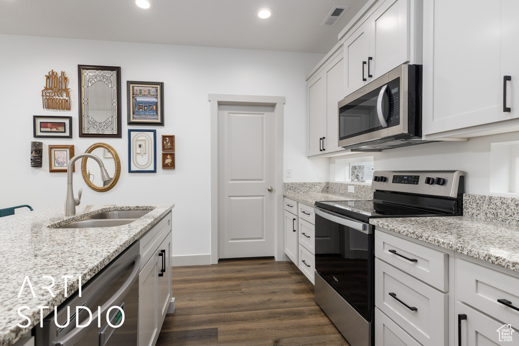 Kitchen featuring a sink, visible vents, stainless steel appliances, dark wood-style flooring, and light stone countertops
