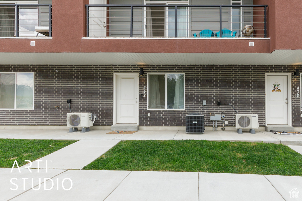 View of exterior entry featuring central air condition unit, a patio, ac unit, and a balcony