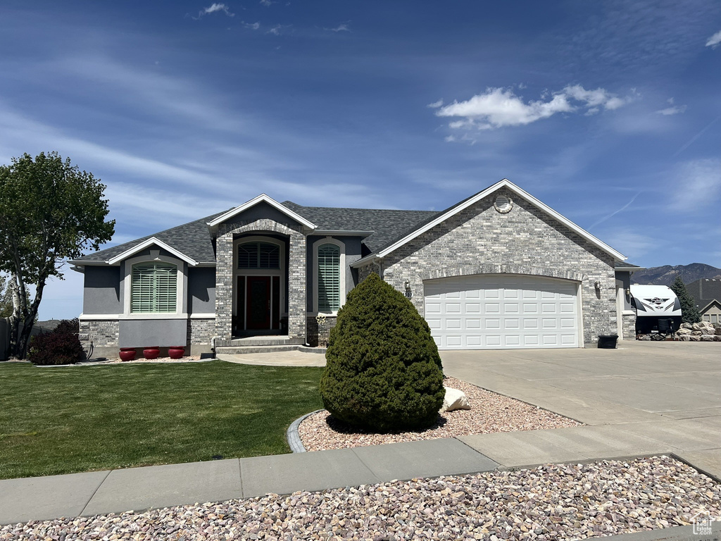 View of front of house with stone siding, concrete driveway, a front lawn, and a garage