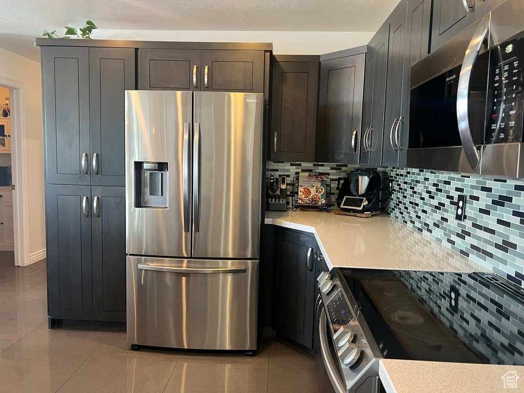 Kitchen featuring light tile patterned floors, backsplash, and appliances with stainless steel finishes
