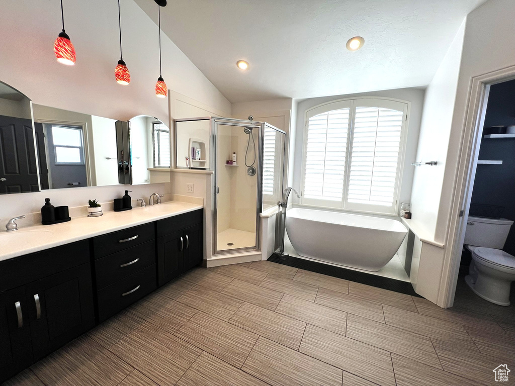 Bathroom featuring a sink, toilet, a stall shower, double vanity, and a freestanding bath