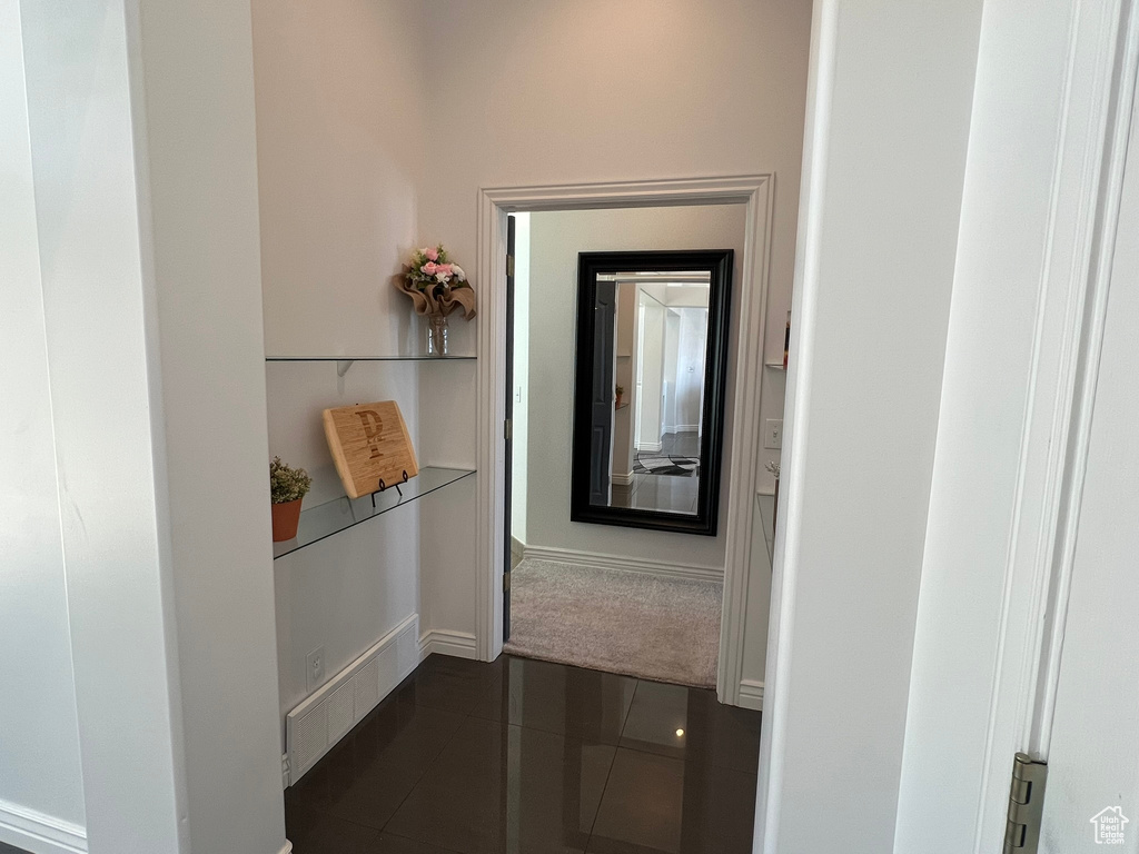 Corridor featuring dark tile patterned floors and baseboards