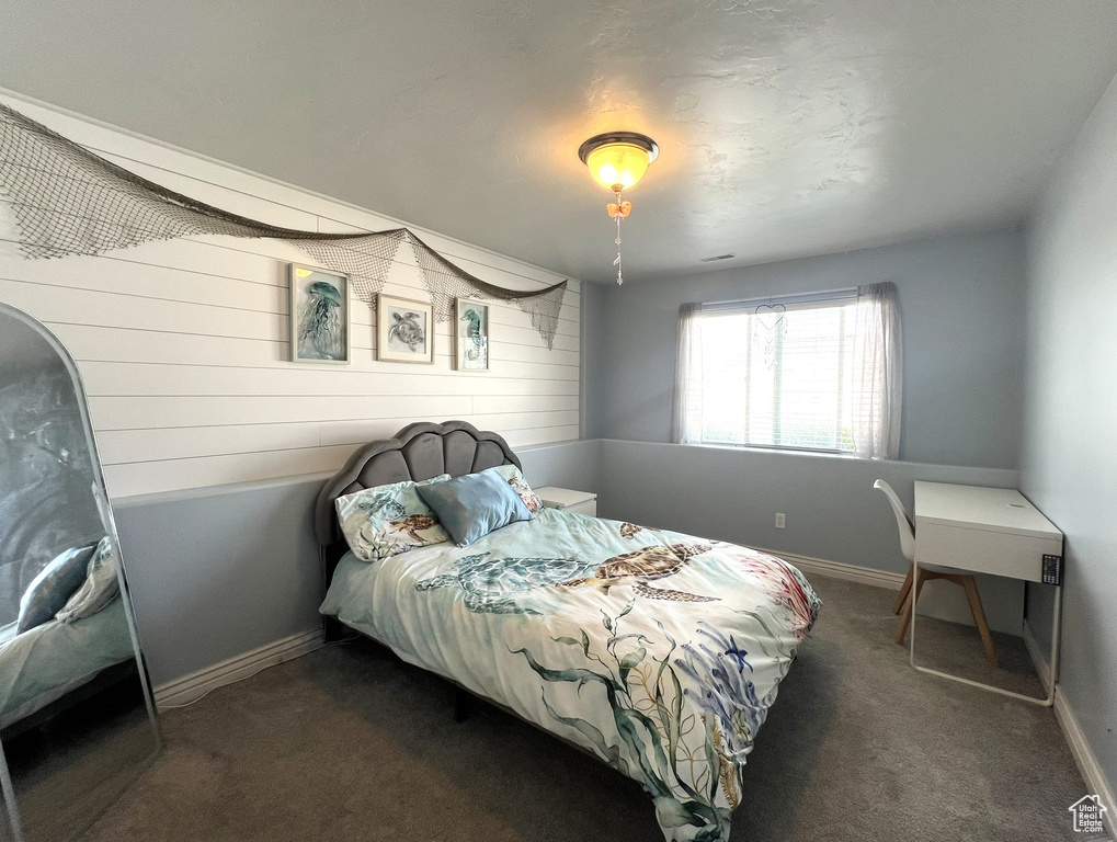 Carpeted bedroom featuring wood walls and baseboards