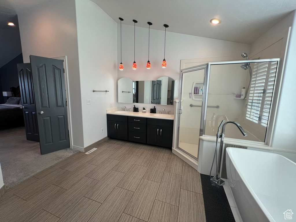Bathroom with double vanity, a soaking tub, a stall shower, and a sink
