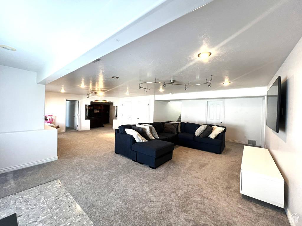 Living room featuring visible vents, arched walkways, and carpet floors