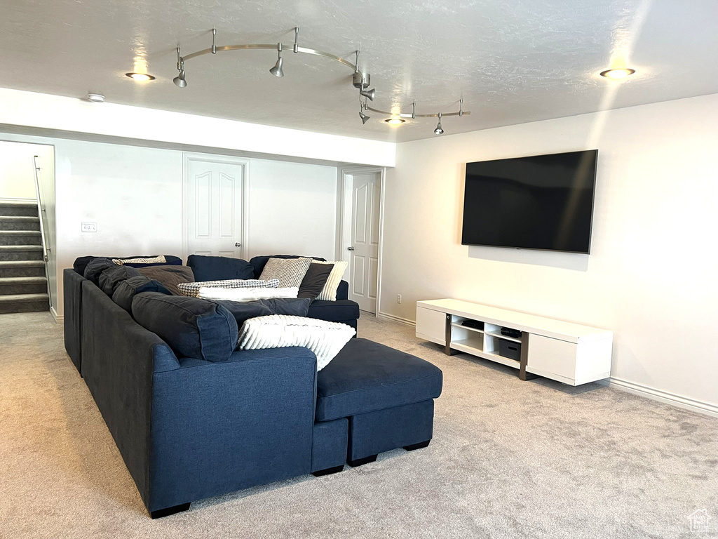 Living area with rail lighting, stairway, baseboards, and carpet floors