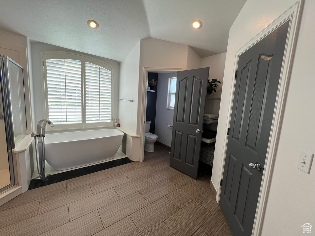 Full bath featuring a washtub, a shower stall, toilet, recessed lighting, and vaulted ceiling