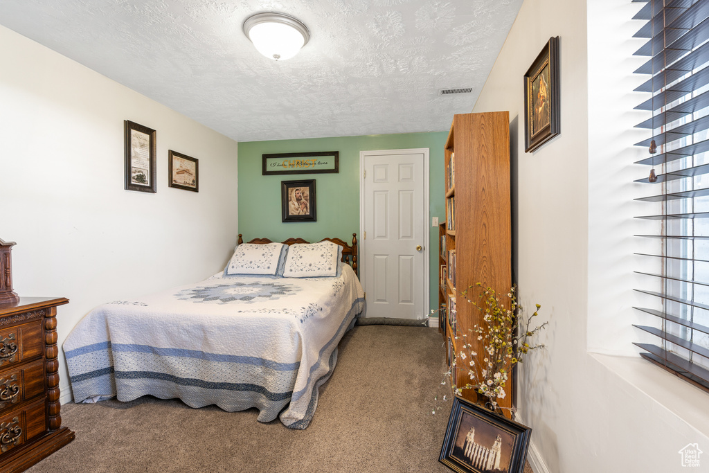 Bedroom with carpet flooring, a textured ceiling, and visible vents