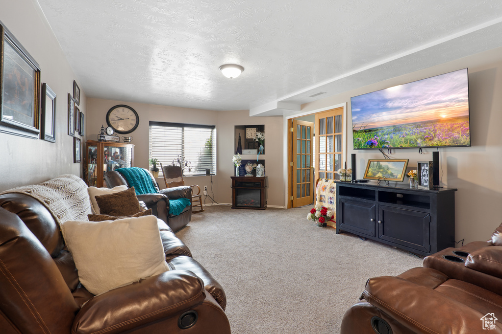 Living room featuring a textured ceiling, light carpet, and baseboards