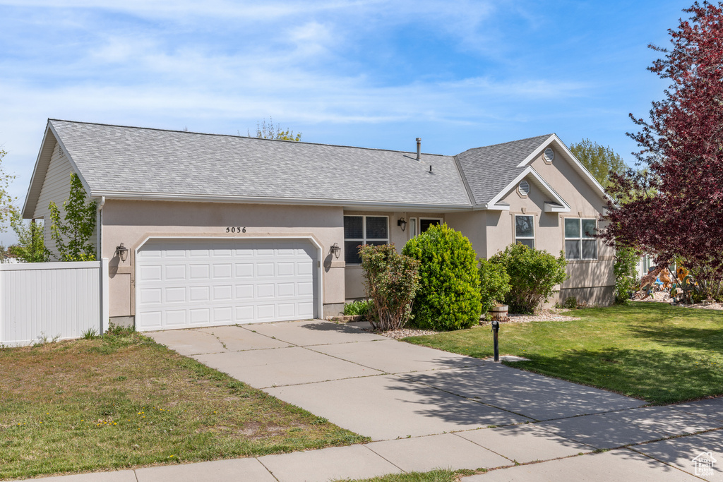 Ranch-style house featuring concrete driveway, roof with shingles, stucco siding, a front lawn, and a garage
