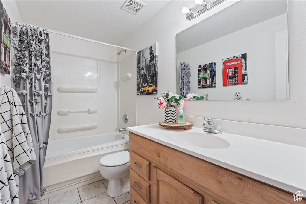 Bathroom with tile patterned flooring, shower / bath combination with curtain, toilet, vanity, and visible vents