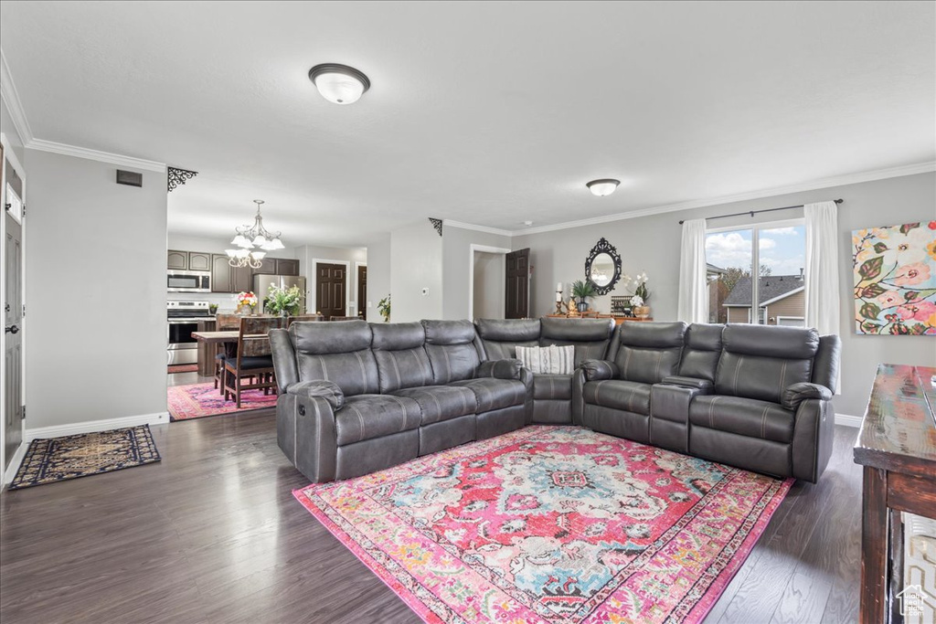 Living room with a chandelier, baseboards, ornamental molding, and dark wood-style flooring