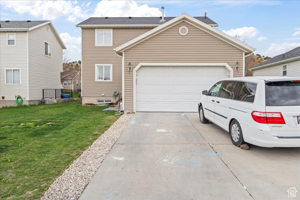 Exterior space featuring concrete driveway, a front yard, and an attached garage