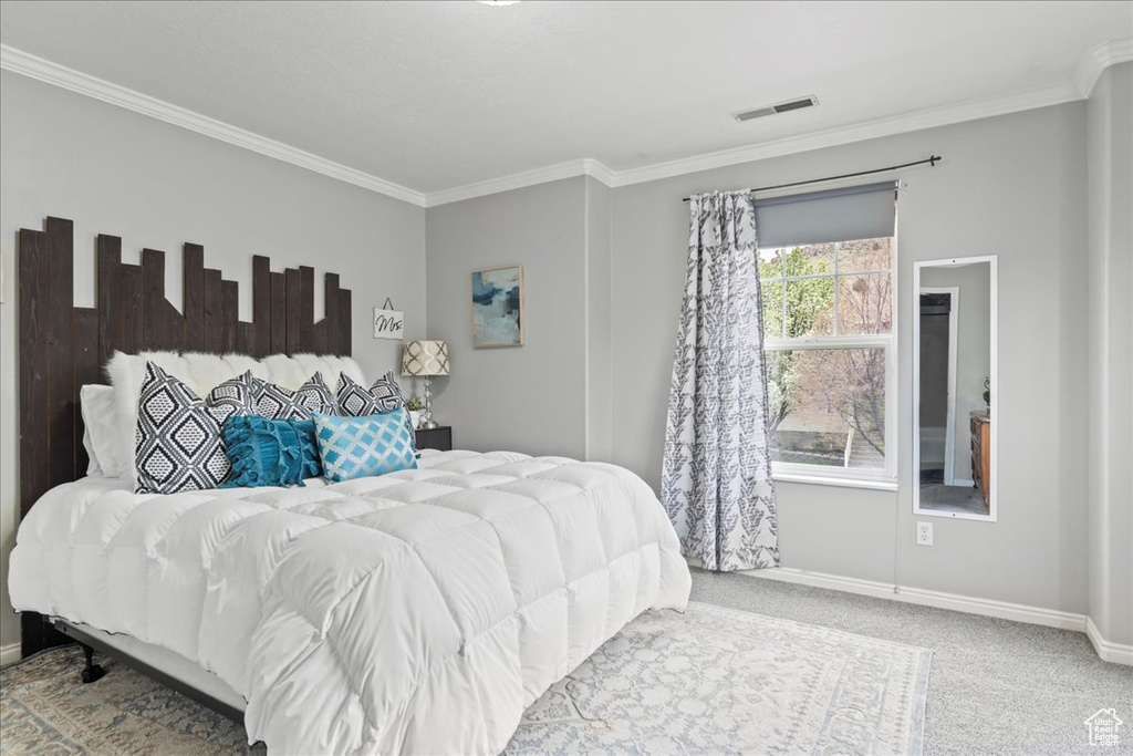 Bedroom with baseboards, visible vents, carpet, and crown molding