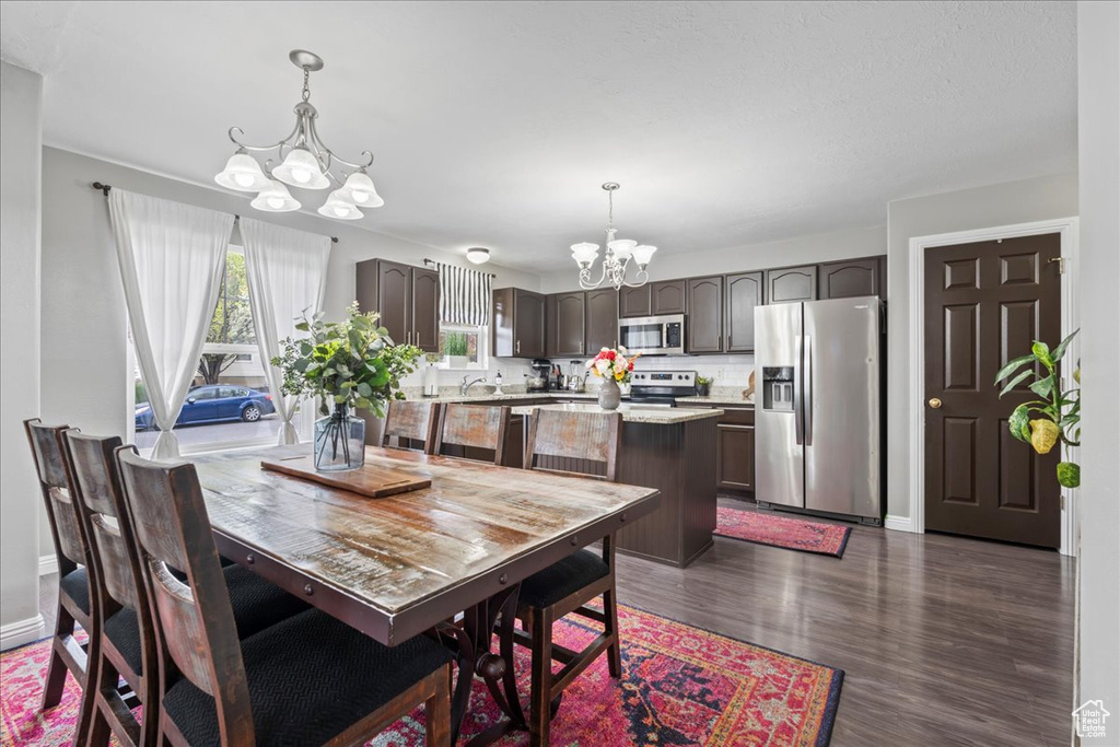 Dining room featuring dark wood-style flooring and a notable chandelier
