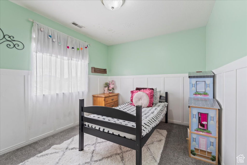Bedroom featuring a wainscoted wall, visible vents, and carpet