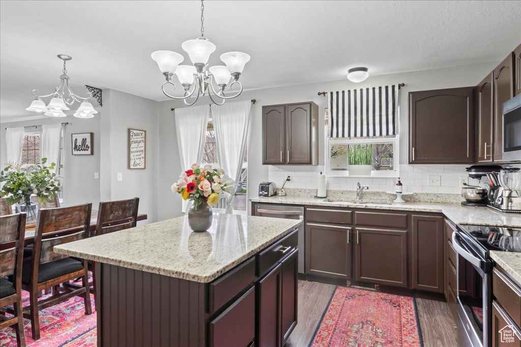 Kitchen with light wood-style floors, stainless steel appliances, a notable chandelier, and a sink