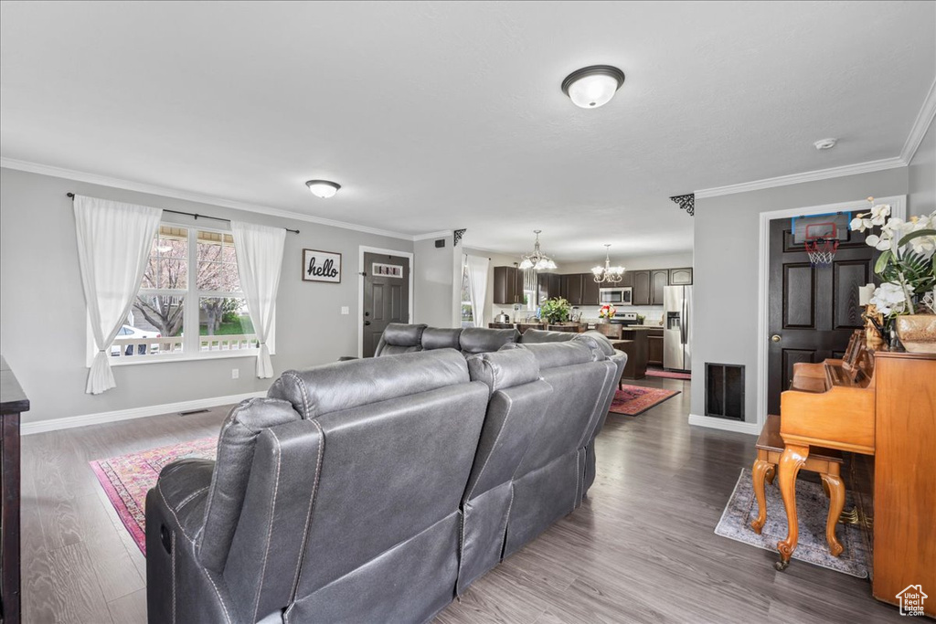 Living area with crown molding, dark wood-style floors, a chandelier, and baseboards