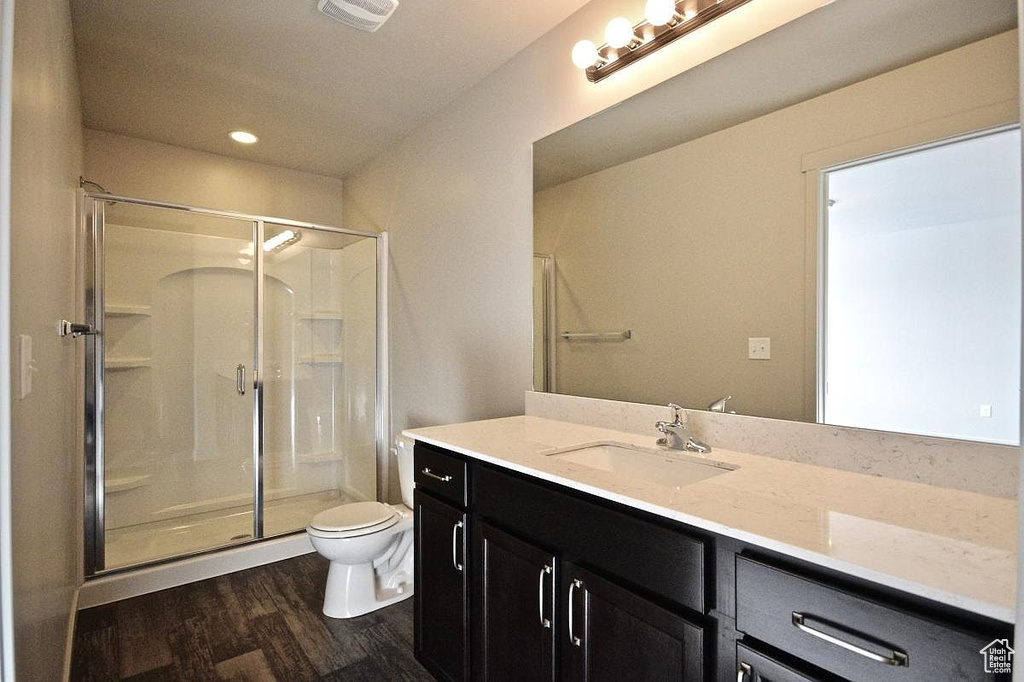 Bathroom featuring toilet, visible vents, a shower stall, and wood finished floors