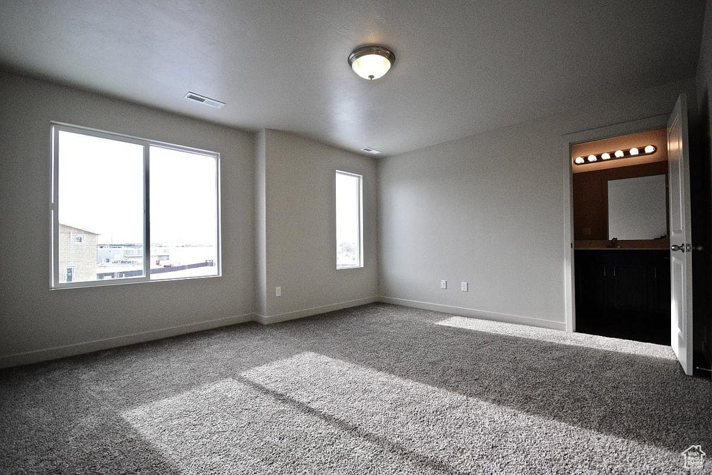 Carpeted spare room featuring baseboards and visible vents